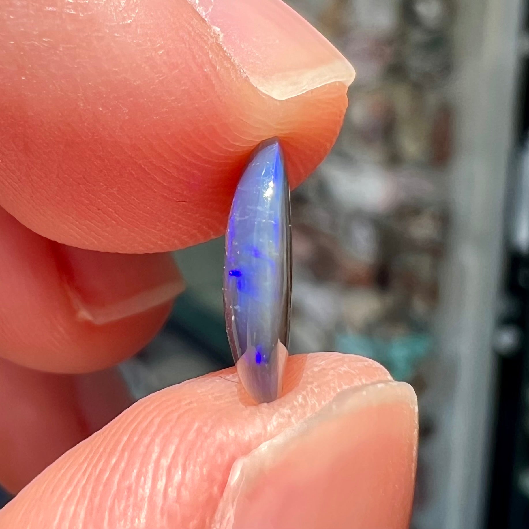 A loose, oval cabochon cut black crystal opal from Lightning Ridge, Australia.