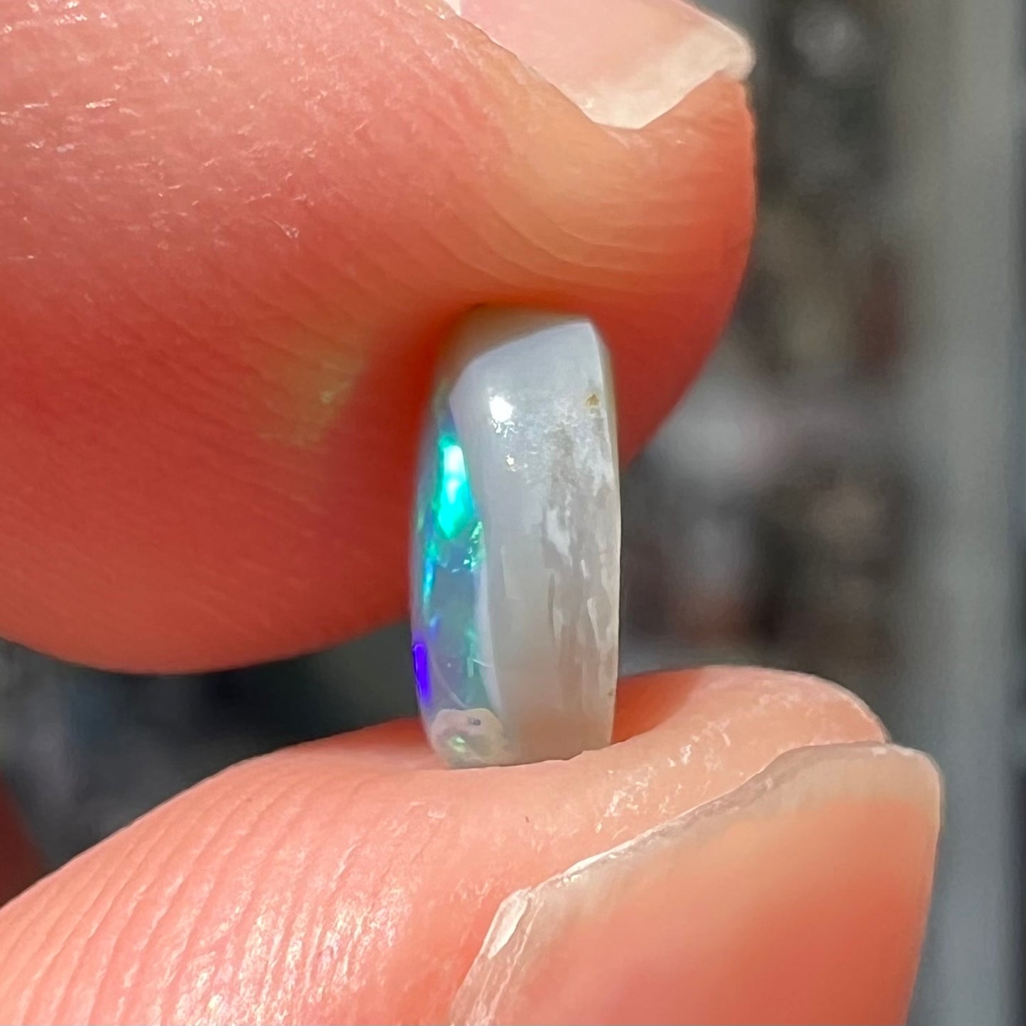 A loose, oval cabochon cut semi-black crystal opal from Lightning Ridge, Australia.