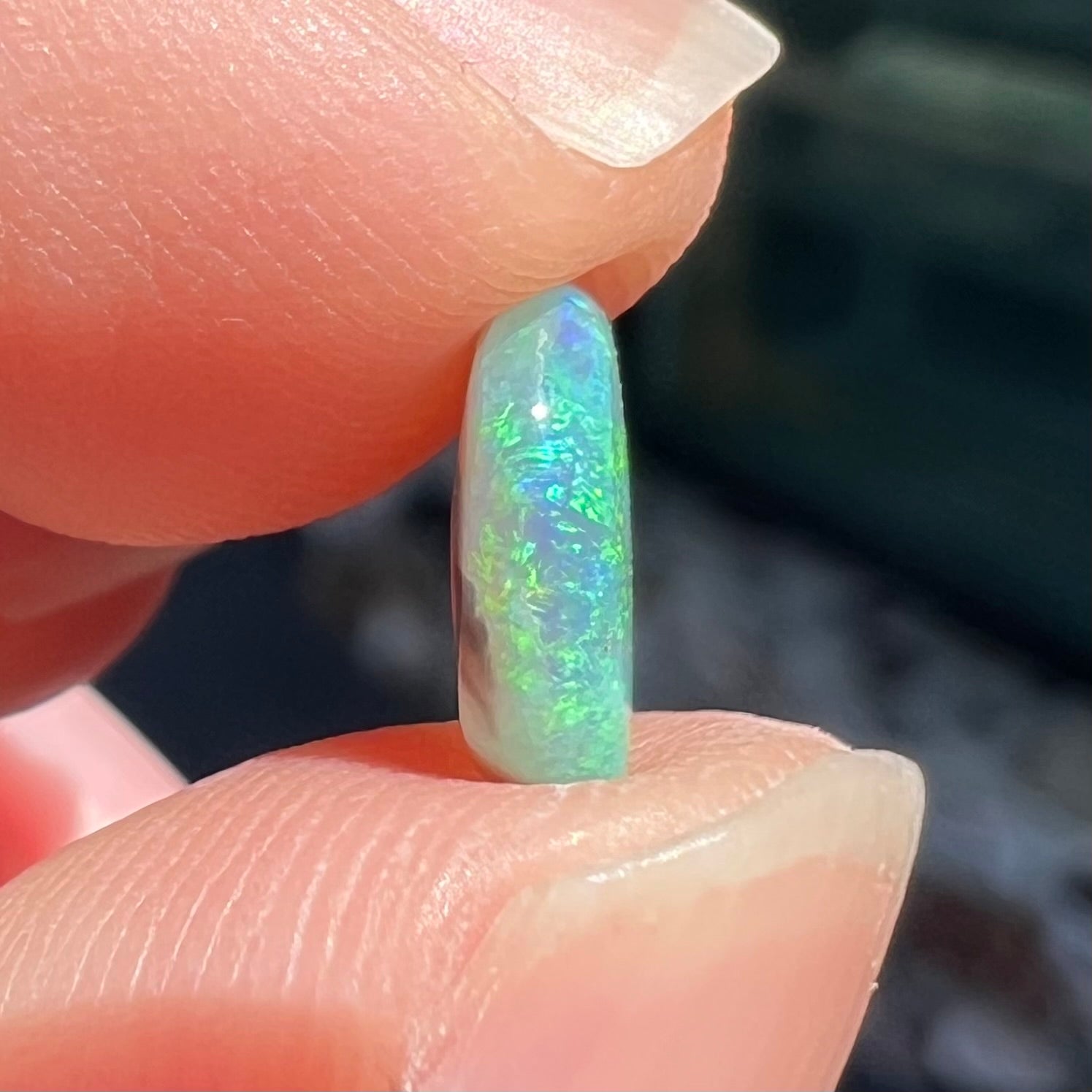 The side of a loose, 1.26 carat semi-black opal stone from Lightning Ridge, Australia.  The opal is green and blue.