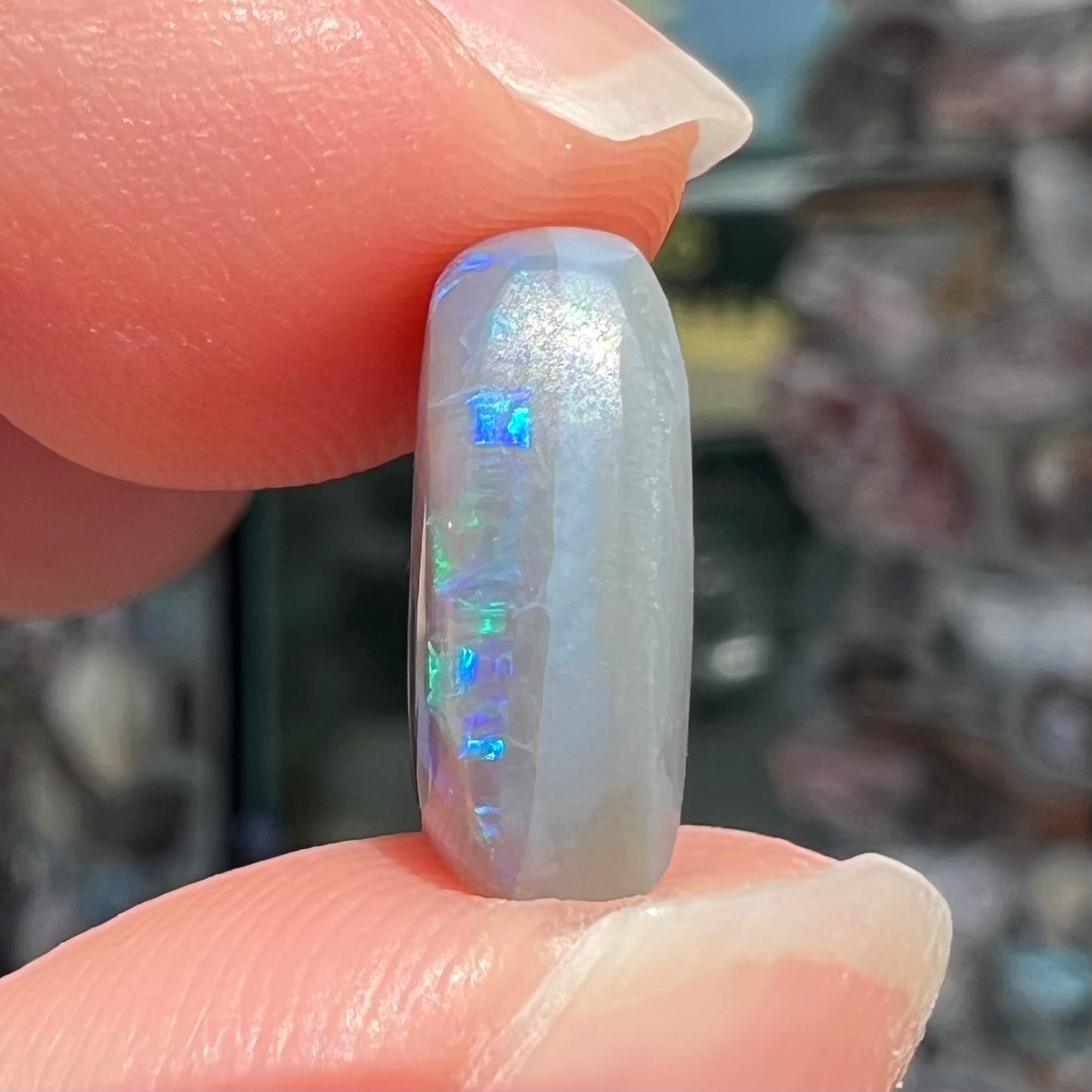 A loose, barrel shaped semi-black opal from Lightning Ridge, Australia.  The opal has blue colors.