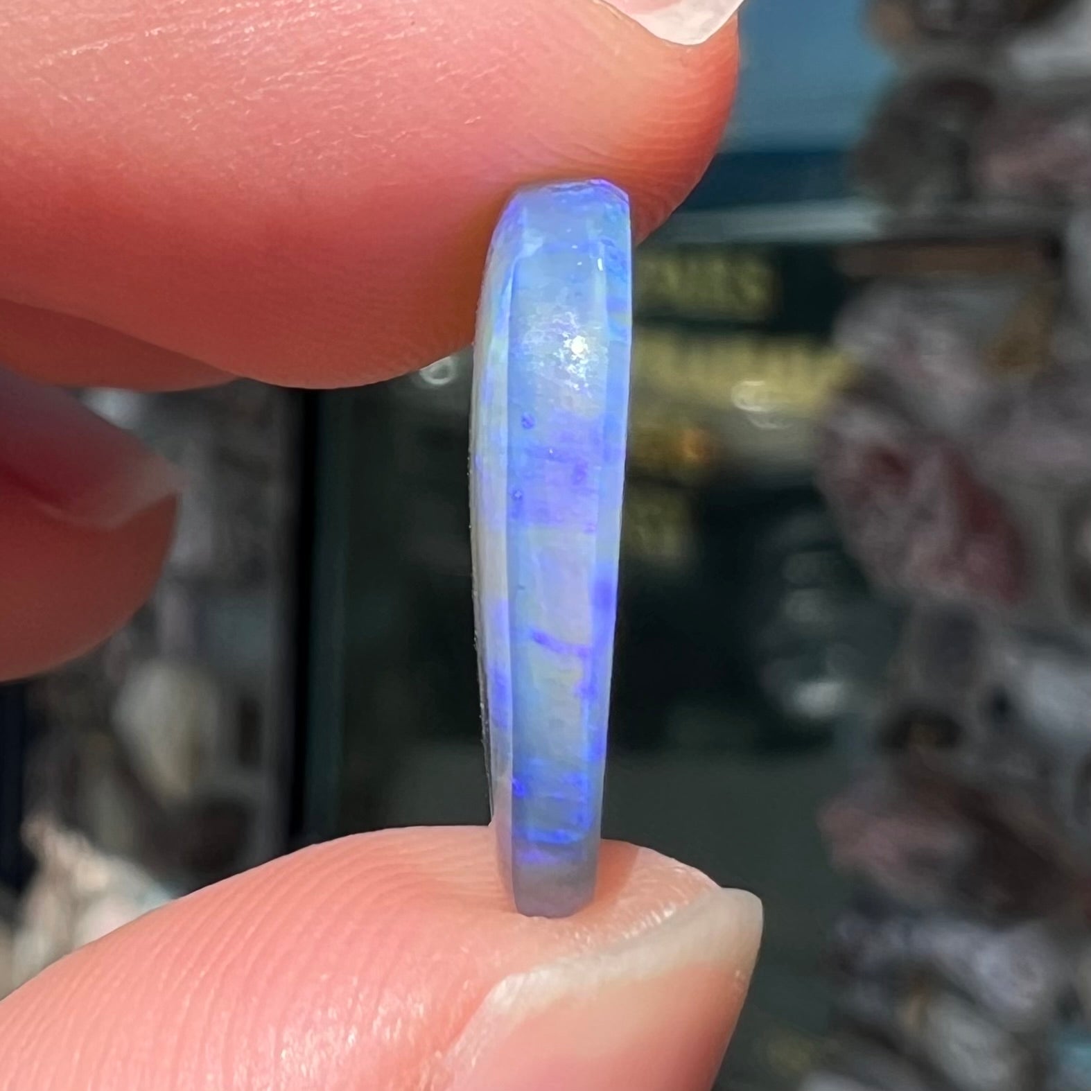 A loose, oval cabochon cut crystal opal from Lightning Ridge, Austalia that weighs 5.16 carats.  The stone has blue and purple colors.