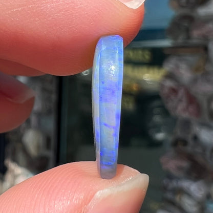 A loose, oval cabochon cut crystal opal from Lightning Ridge, Austalia that weighs 5.16 carats.  The stone has blue and purple colors.