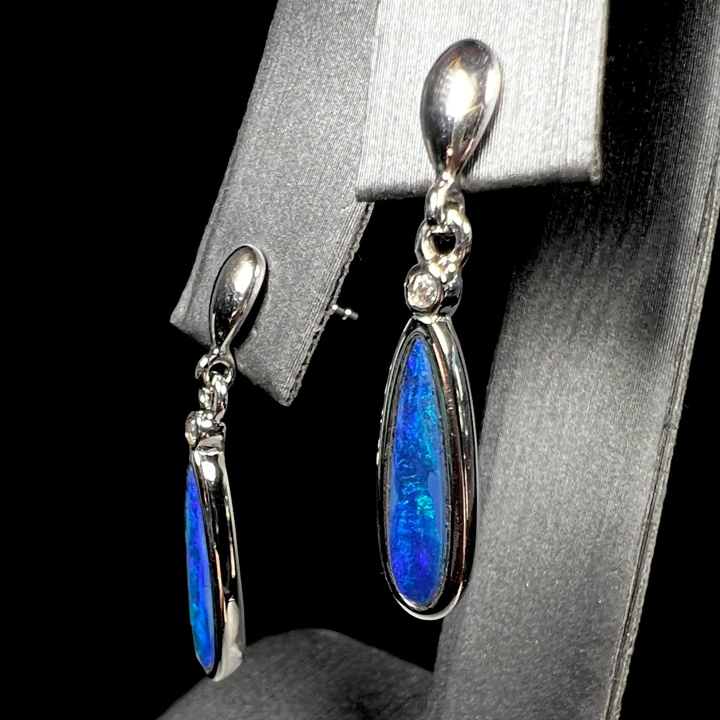 A pair of sterling silver dangle earrings mounted with pear shaped black opal doublets.