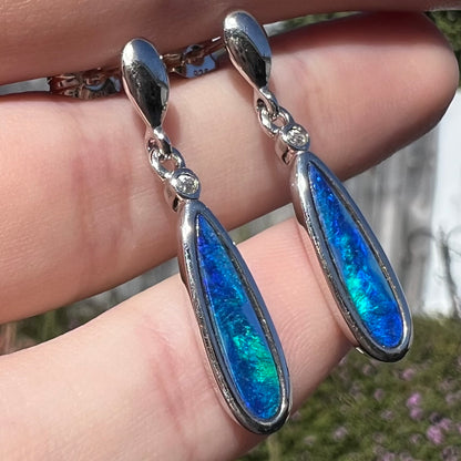 A pair of sterling silver dangle earrings mounted with pear shaped black opal doublets.