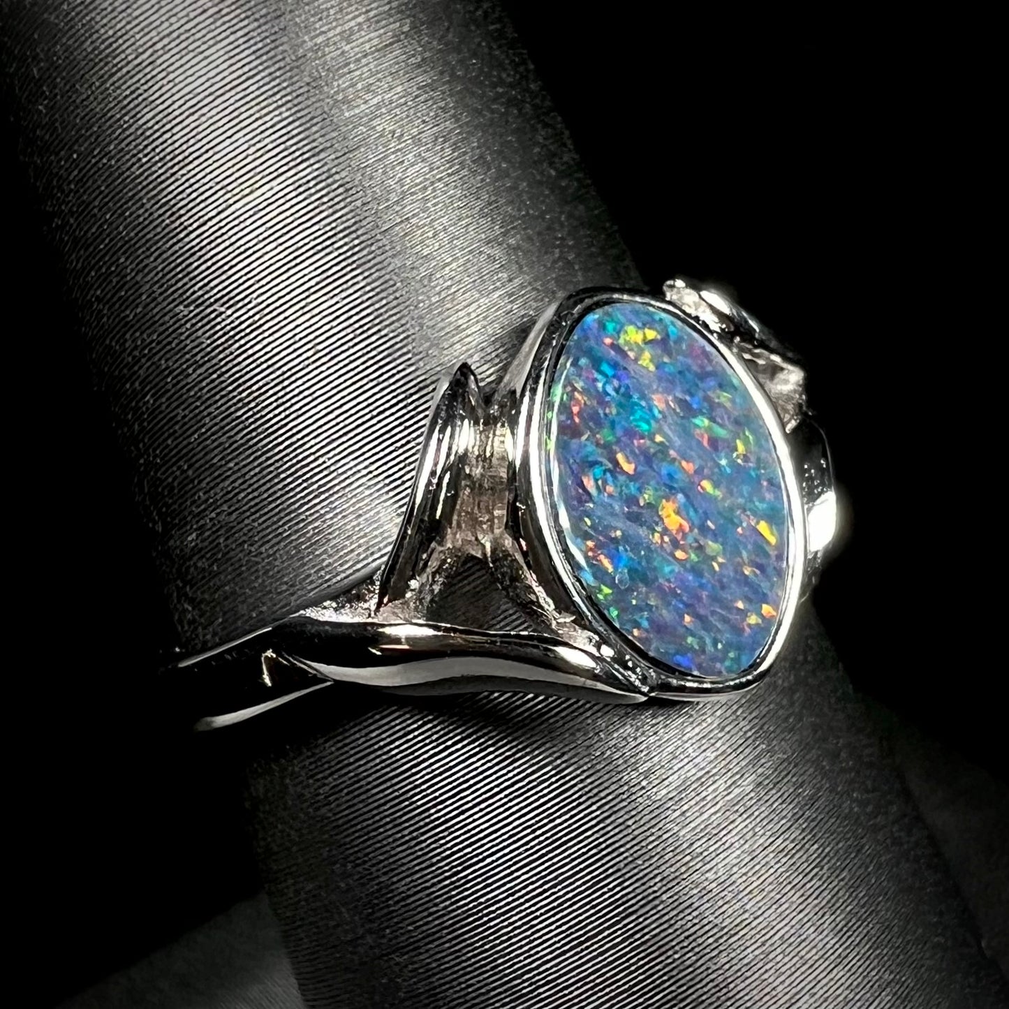 A silver leaf-style ring mounted with a multicolor black opal doublet.