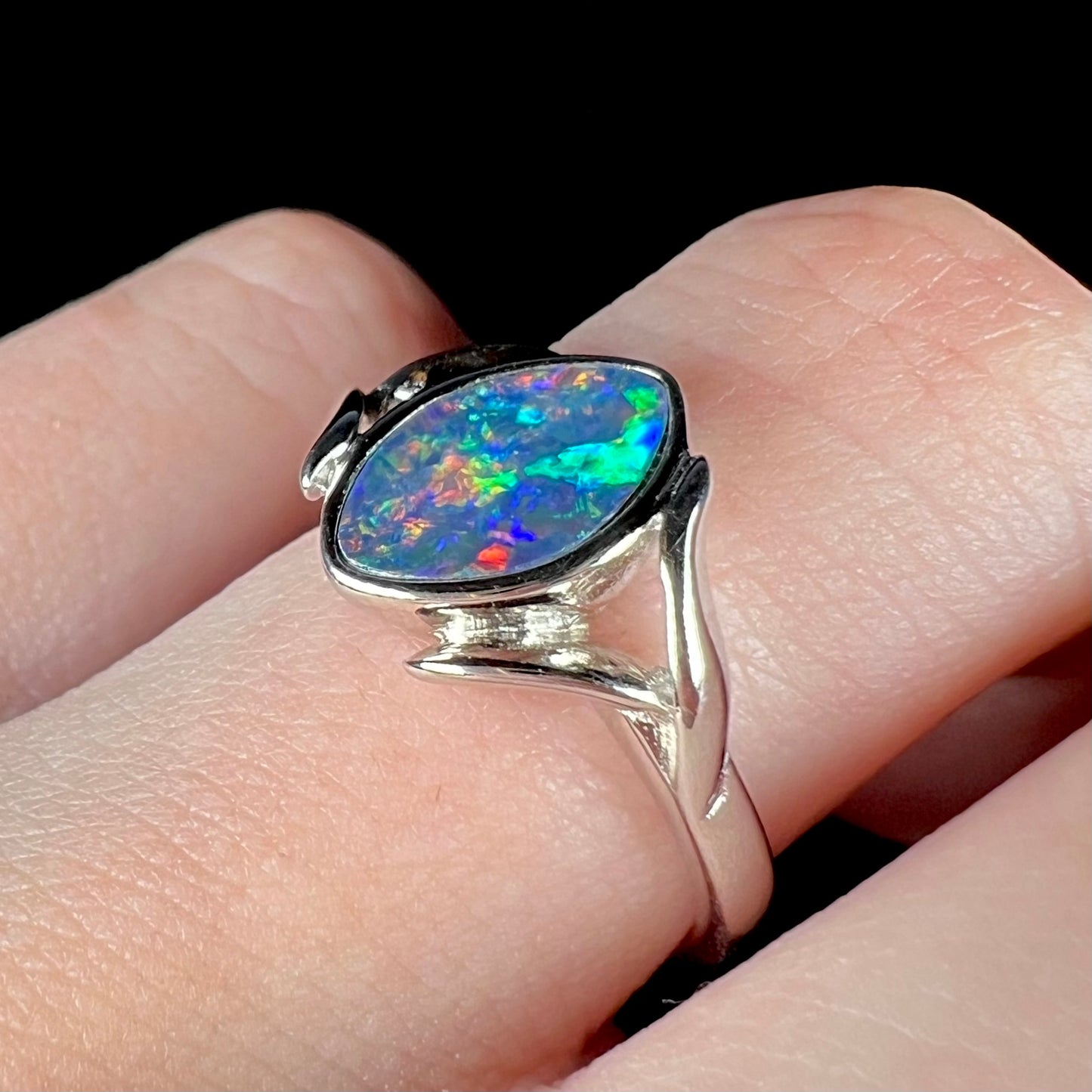 A sterling silver ring mounted with a marquise cut black opal doublet.  The opal has red fire.