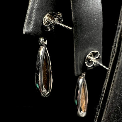 A pair of sterling silver, pear shaped opal doublet dangle earrings.  The opals have a gray body tone with red fire.