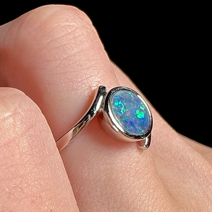 A sterling silver bypass ring bezel-set with a round cut black opal doublet.