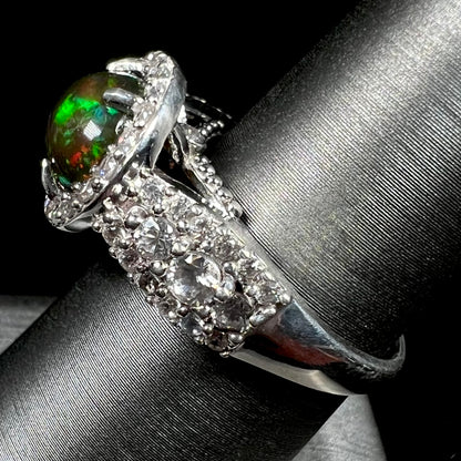 A CZ-accented sterling silver halo ring mounted with a smoked Ethiopian fire opal.  The opal plays green, red, and blue colors.