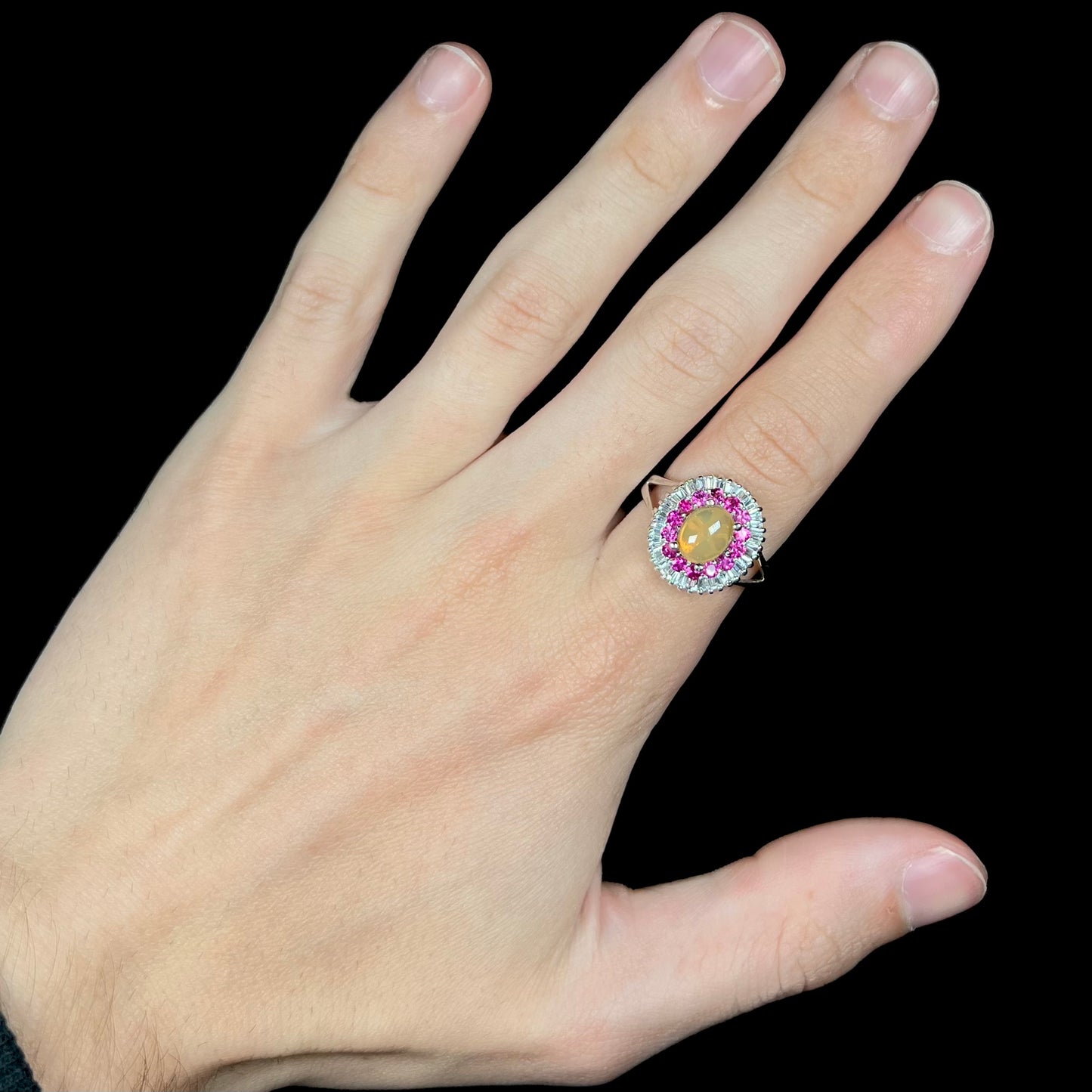 A sterling silver Ethiopian opal ring mounted with a halo of white CZs and another halo of synthetic pink sapphires.