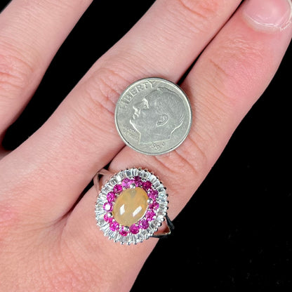 A sterling silver Ethiopian opal ring mounted with a halo of white CZs and another halo of synthetic pink sapphires.