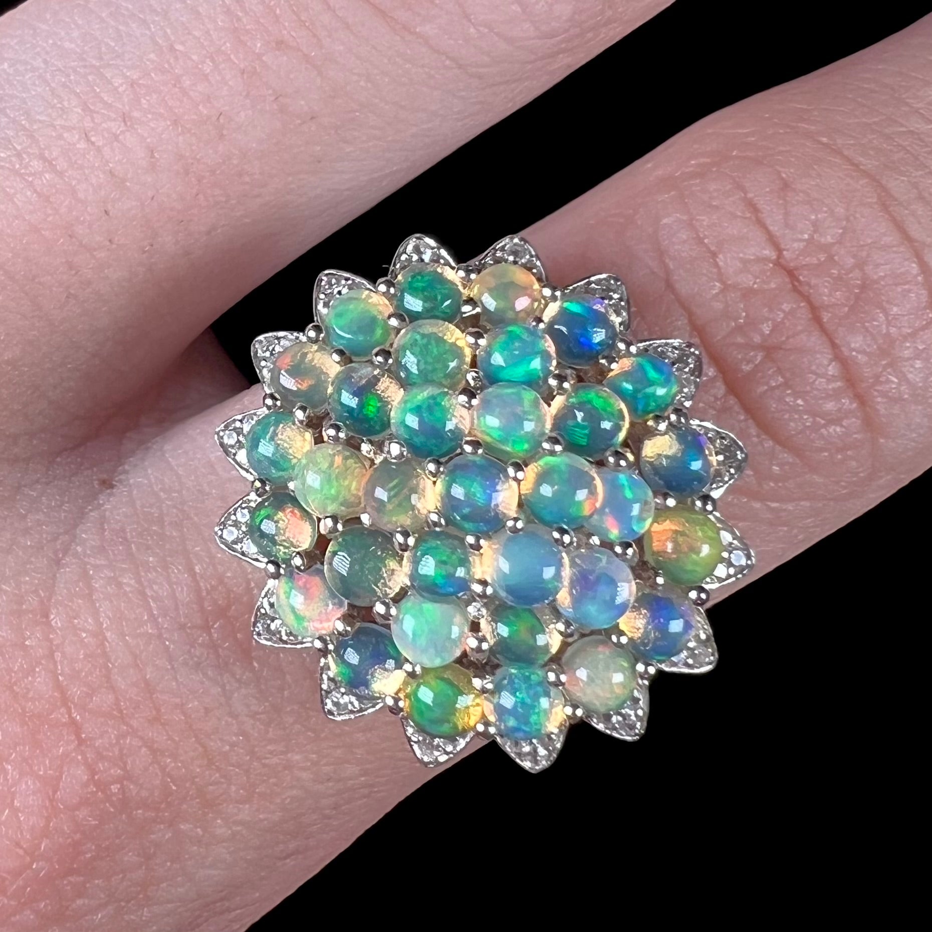 A sterling silver cluster flower ring mounted with 33 round Ethiopian fire opals.