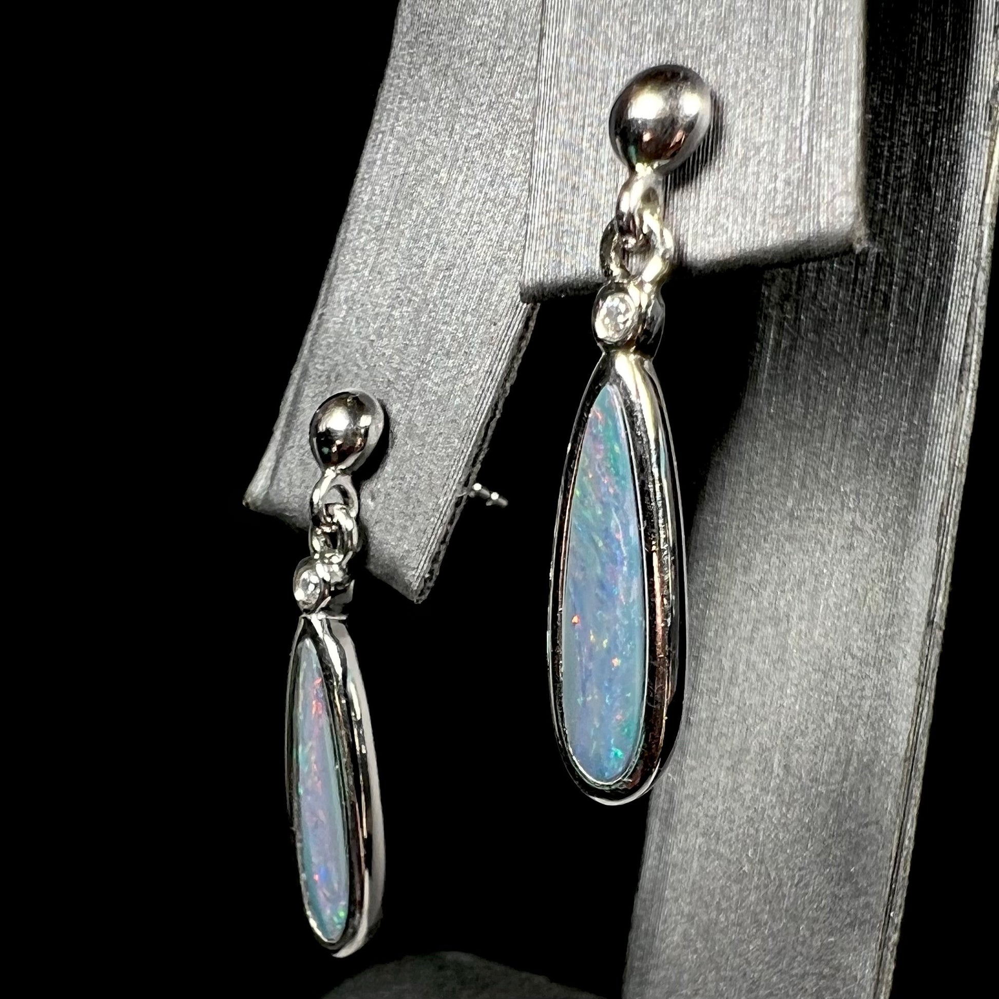 A pair of sterling silver, pear shaped opal doublet dangle earrings.  The opals have a gray body tone with red fire.