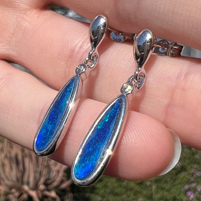 A pair of sterling silver dangle earrings mounted with pear shaped black opal doublets.