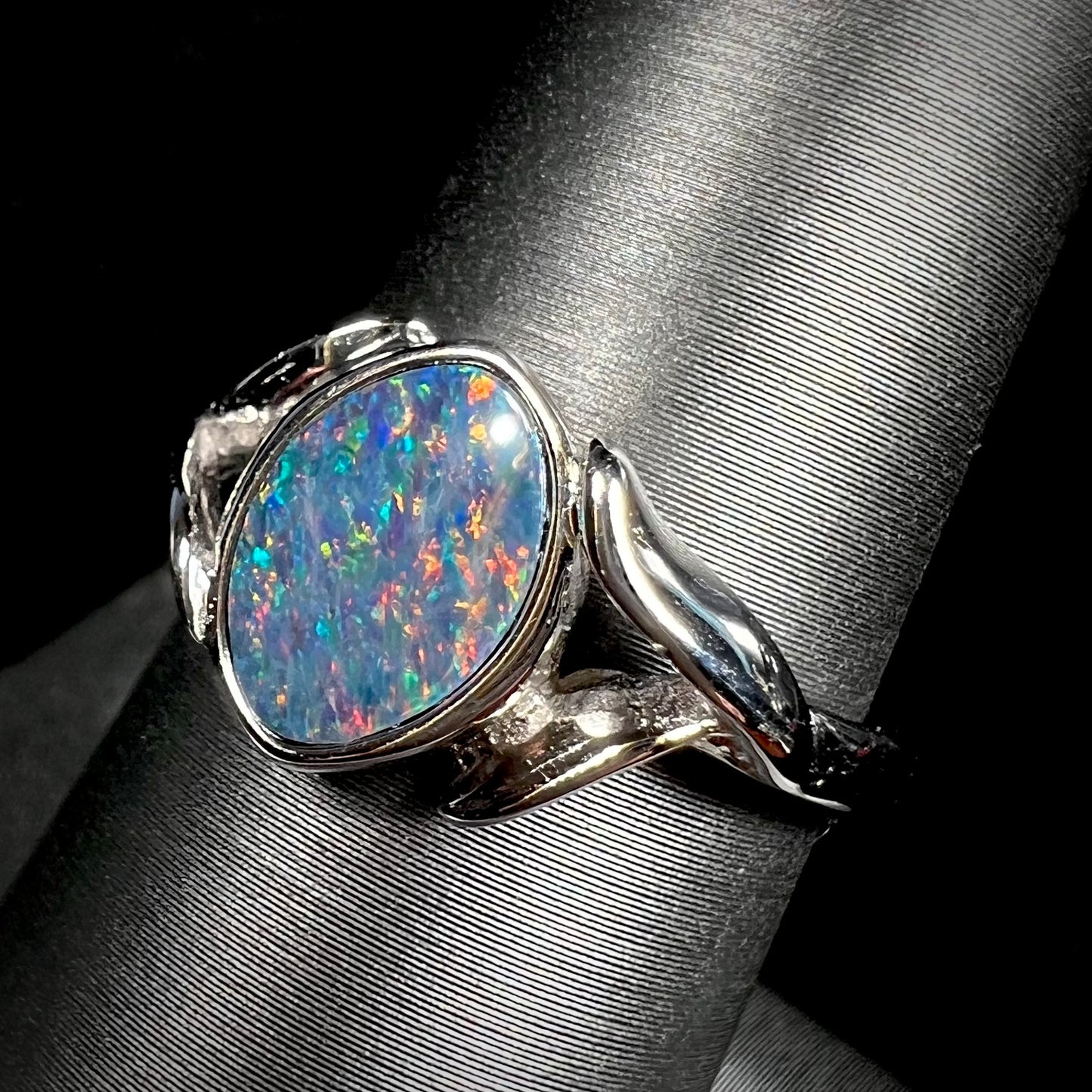 A silver leaf-style ring mounted with a multicolor black opal doublet.