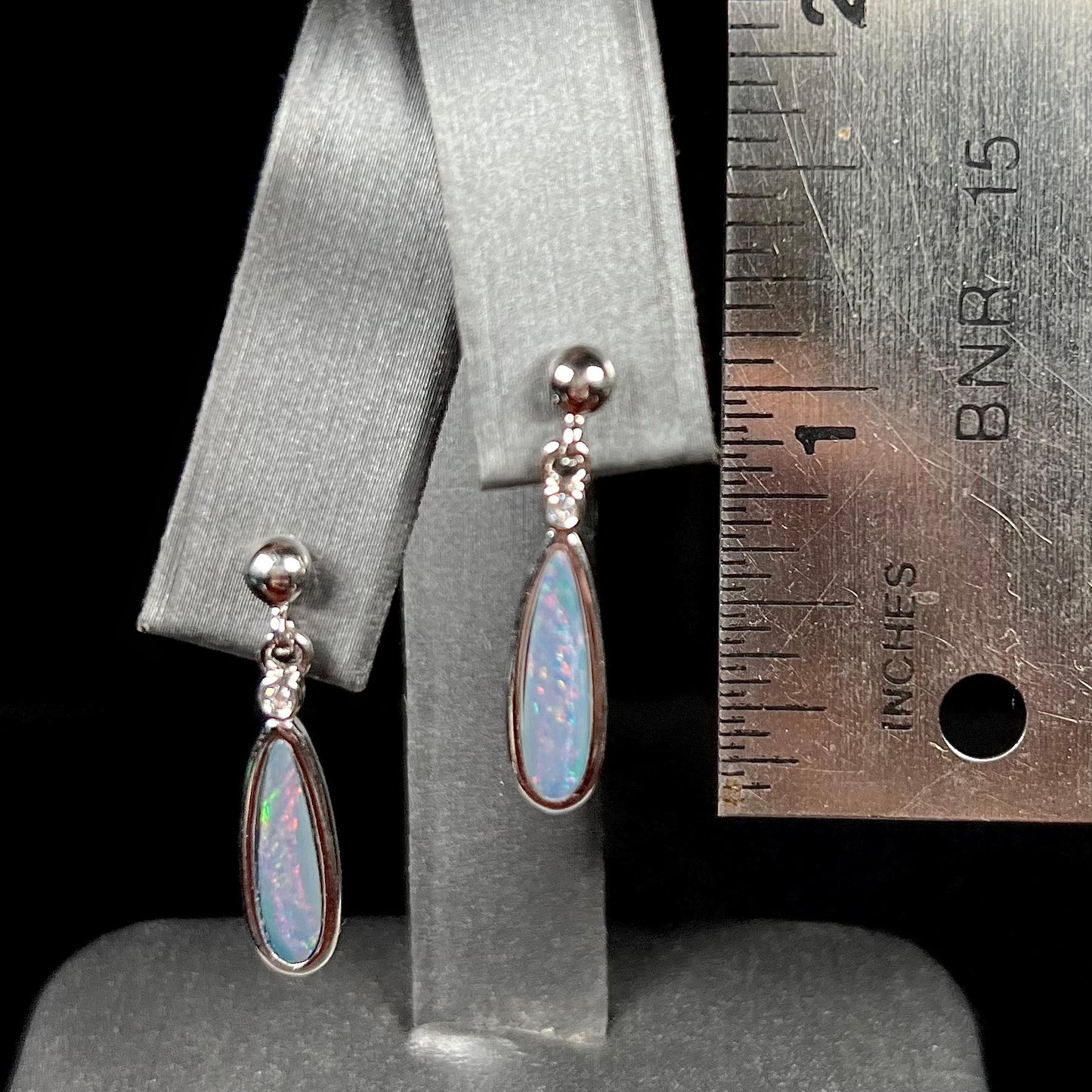 A pair of sterling silver, pear shaped opal doublet dangle earrings.  The opals have a gray body tone with red fire.