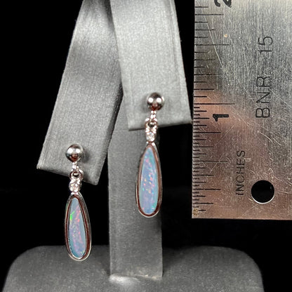 A pair of sterling silver, pear shaped opal doublet dangle earrings.  The opals have a gray body tone with red fire.