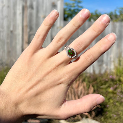 A CZ-accented sterling silver halo ring mounted with a smoked Ethiopian fire opal.  The opal plays green, red, and blue colors.