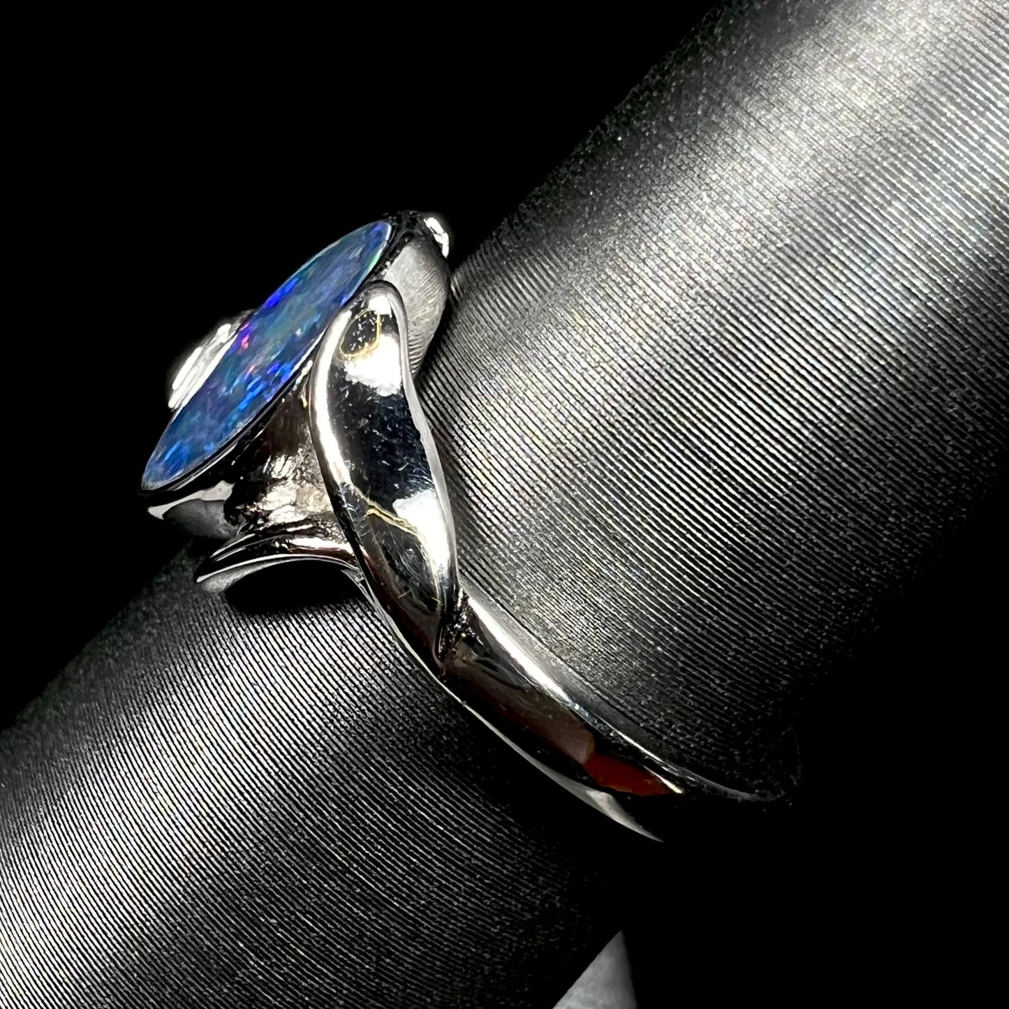 A sterling silver ring mounted with a marquise cut black opal doublet.  The opal has red fire.