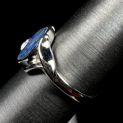 A sterling silver ring mounted with a marquise cut black opal doublet.  The opal has red fire.