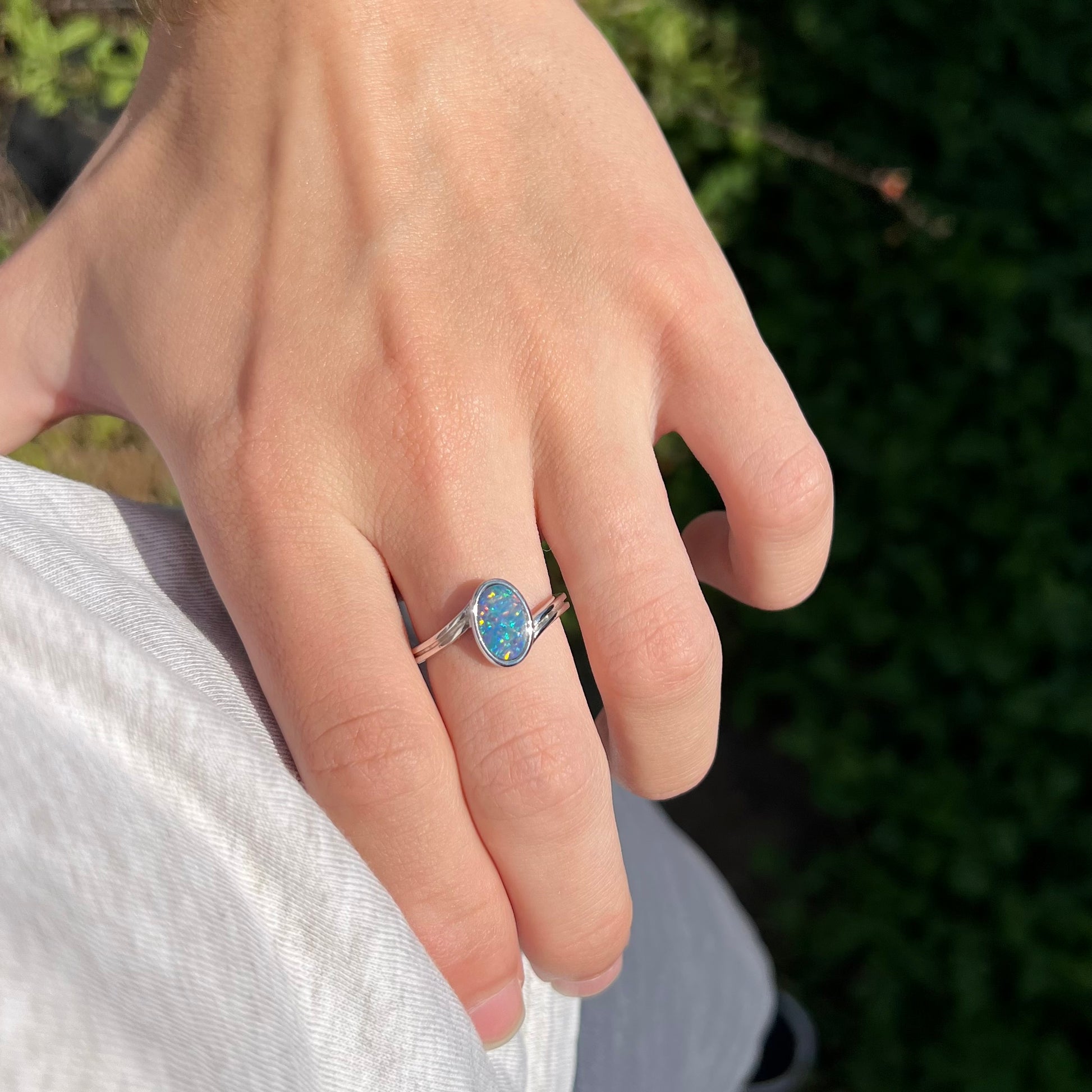 A sterling silver ring bezel-set with an oval shaped black opal doublet.  The opal has red and blue fire.