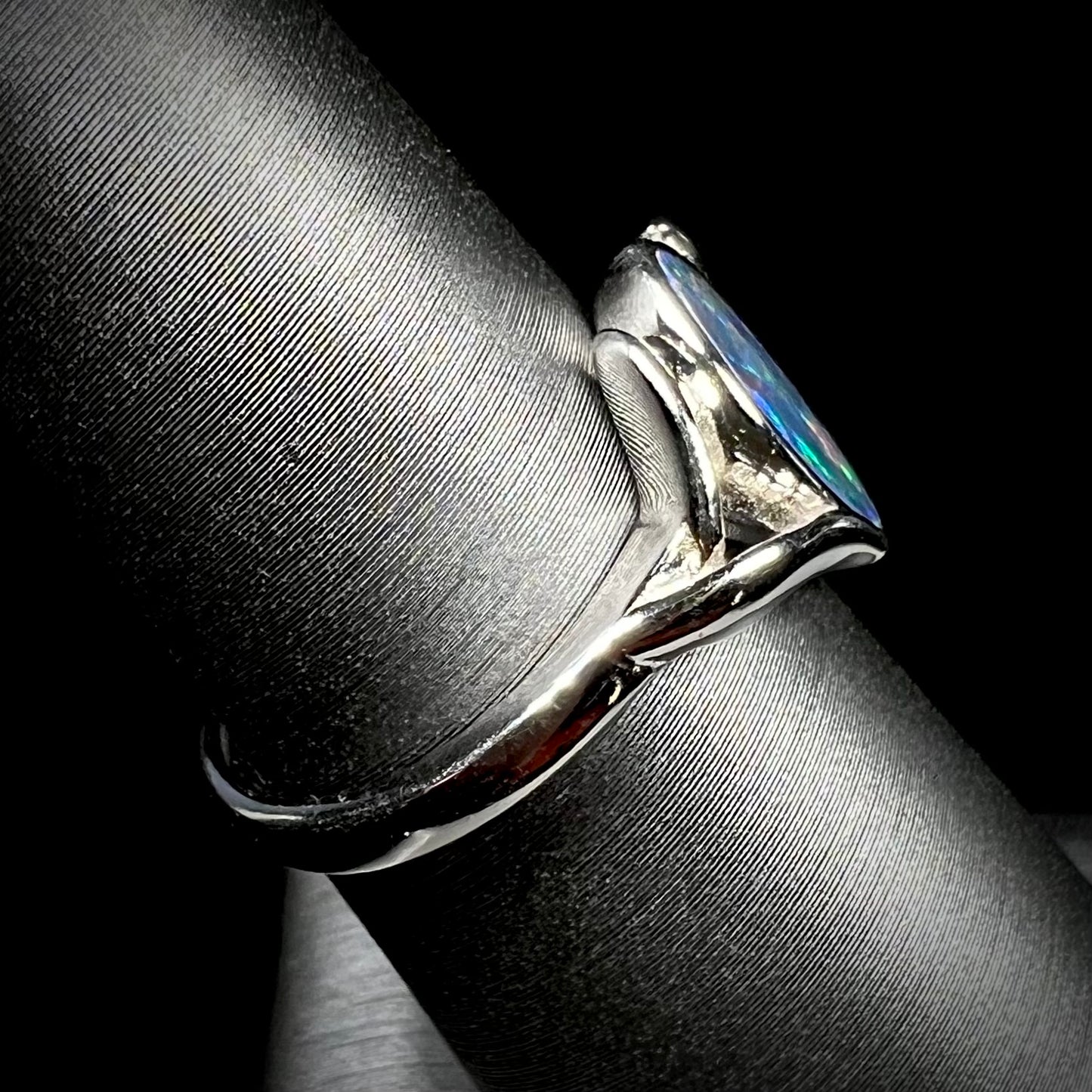 A sterling silver ring mounted with a marquise cut black opal doublet.  The opal has red fire.