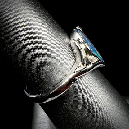 A sterling silver ring mounted with a marquise cut black opal doublet.  The opal has red fire.