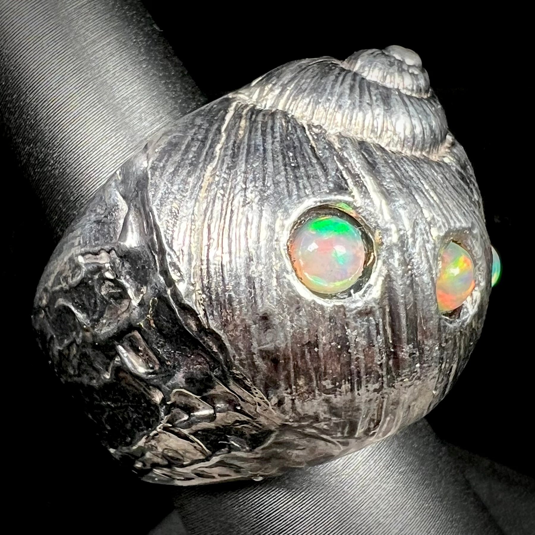 A large, three dimensional sterling silver snail seashell ring set with three round Ethiopian fire opal stones.