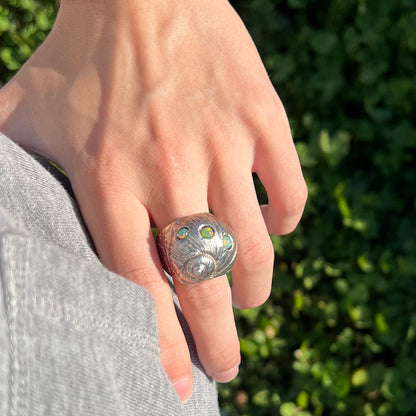 A large, three dimensional sterling silver snail seashell ring set with three round Ethiopian fire opal stones.