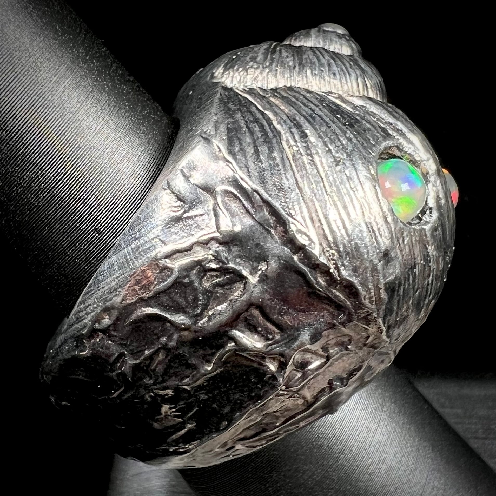 A large, three dimensional sterling silver snail seashell ring set with three round Ethiopian fire opal stones.