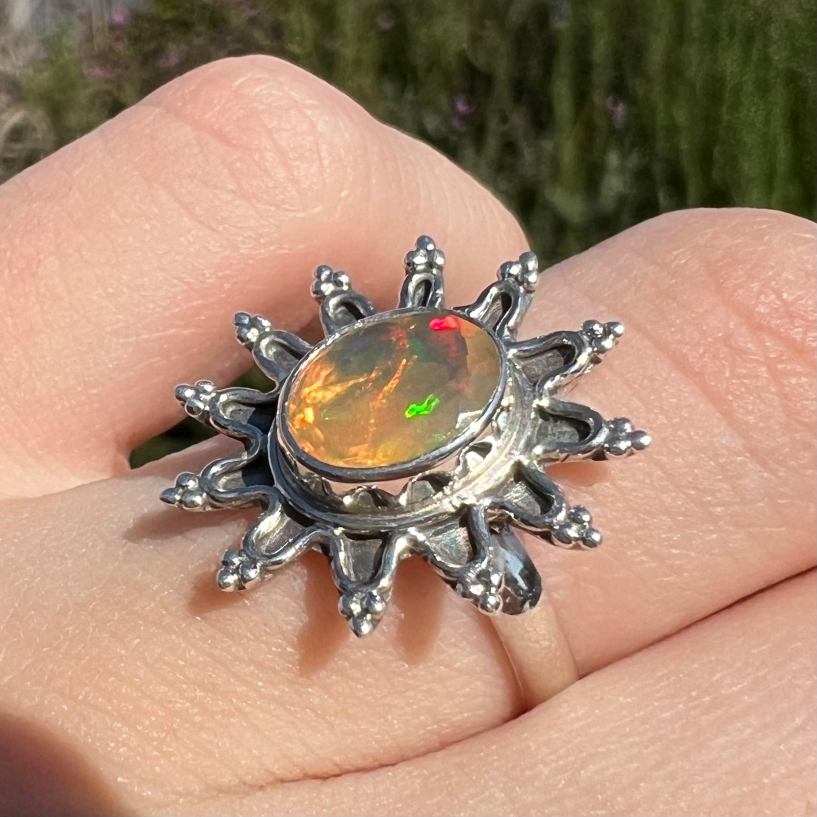 A sterling silver sunburst-style ring mounted with a faceted oval cut Ethiopian fire opal.