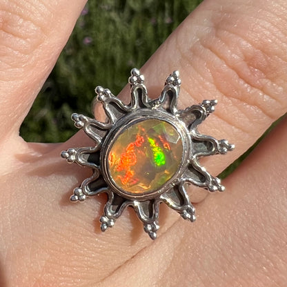 A sterling silver sunburst-style ring mounted with a faceted oval cut Ethiopian fire opal.