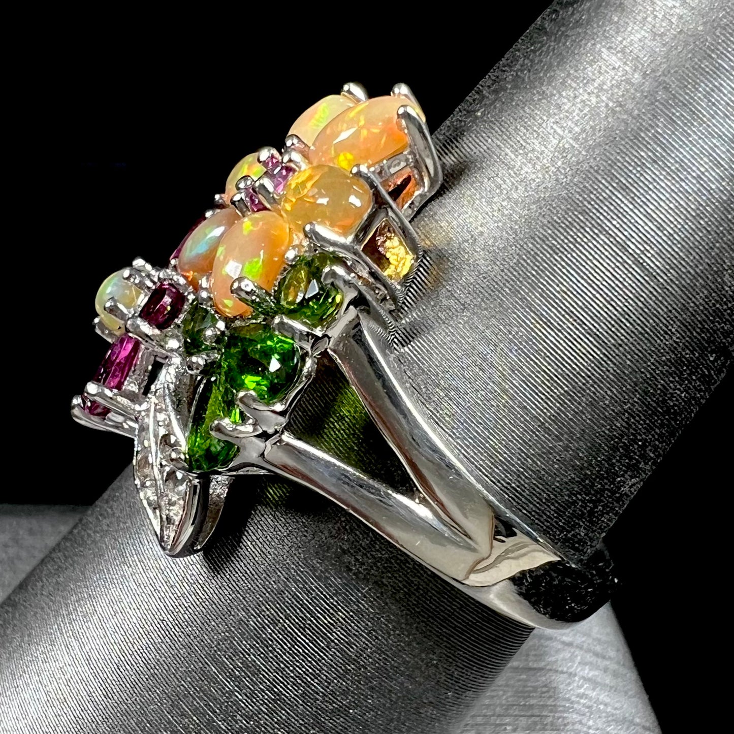 A ladies' gemstone flower design cluster ring set with Ethiopian fire opals, chrome diopsides, rhodolite garnets, and white topaz stones.