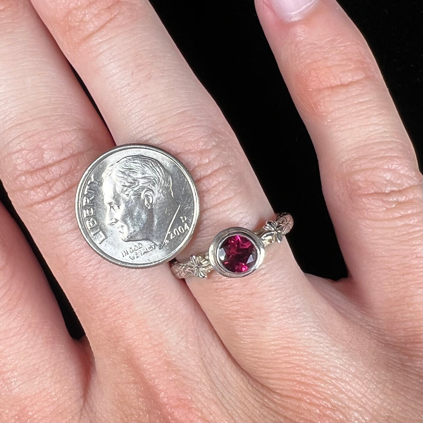 A ladies' sterling silver purple rhodonite garnet solitaire ring.  The shank has an etched floral leaf design.