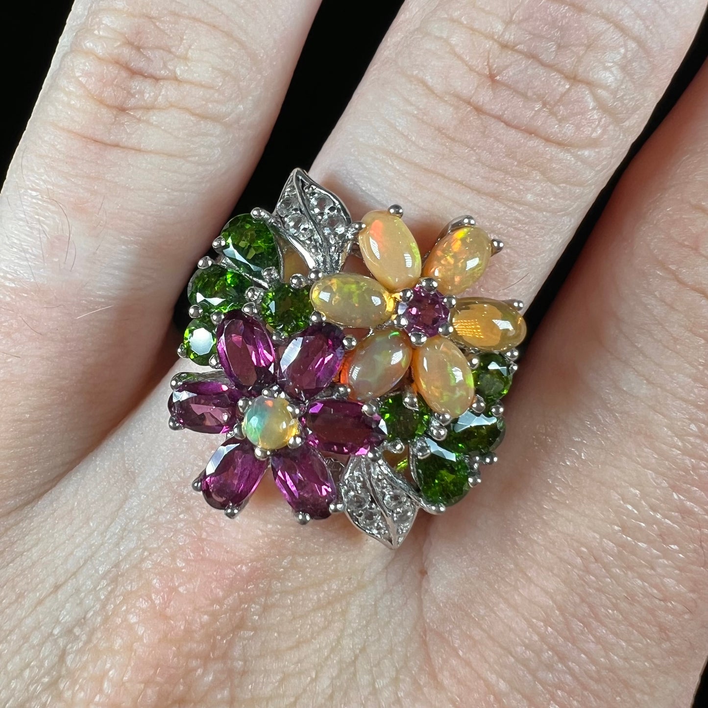 A ladies' gemstone flower design cluster ring set with Ethiopian fire opals, chrome diopsides, rhodolite garnets, and white topaz stones.