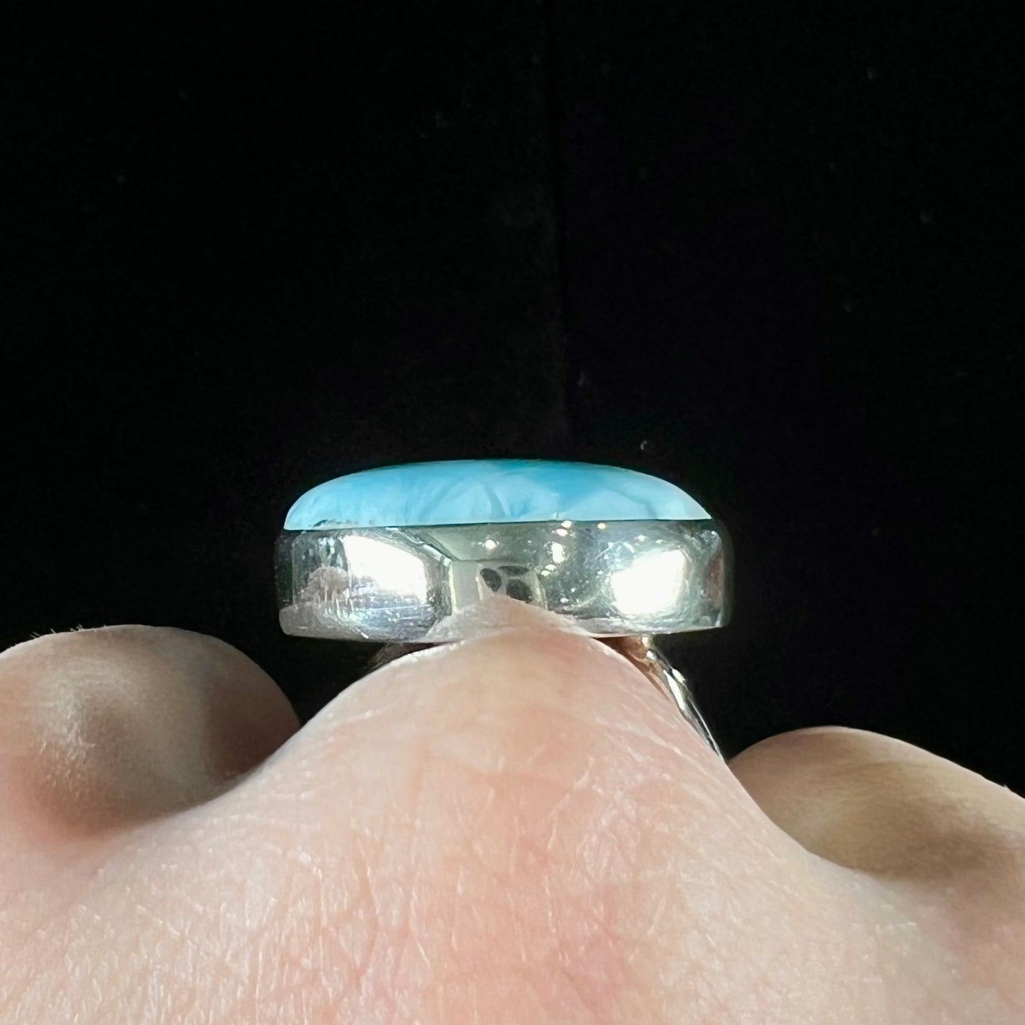 A ladies' large, pear shaped larimar solitaire ring in sterling silver.  The larimar stone measures an inch long.