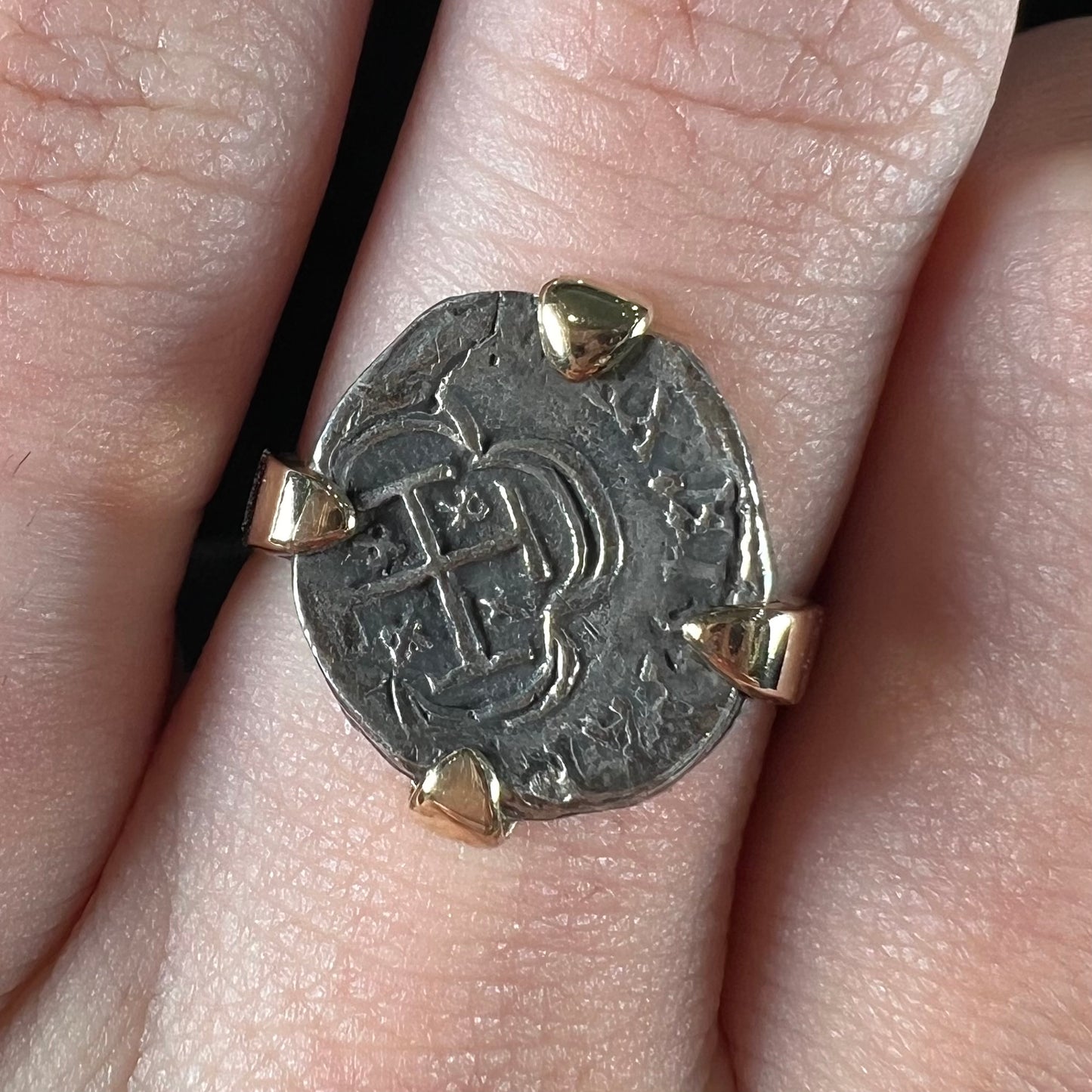 A silver Atocha 1 reale coin replica set in a yellow gold ring.