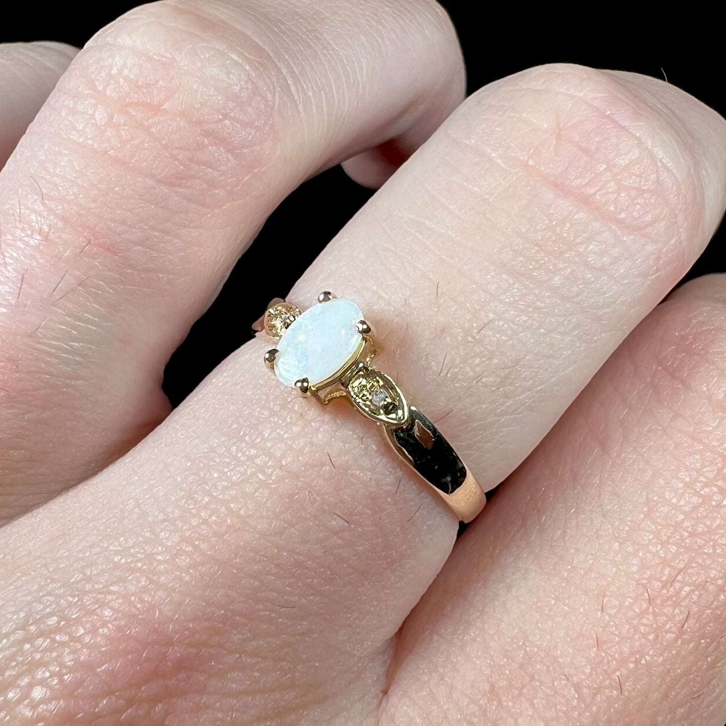 A dainty ladies' yellow gold opal and diamond ring.  The opal has subtle play of color.