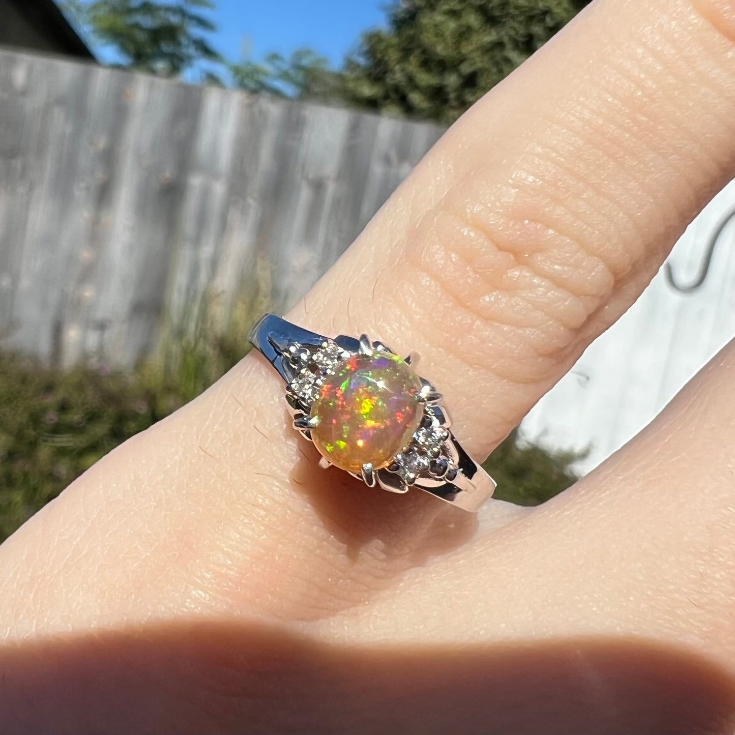 A platinum, diamond accented ring prong-set with an oval cabochon cut Mexican fire opal.