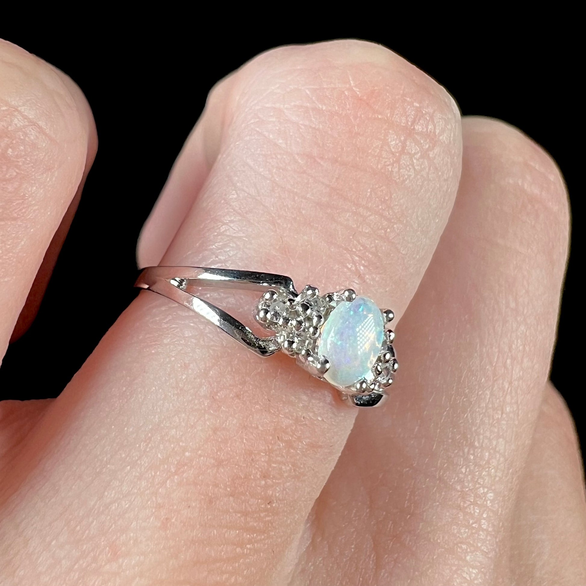 A ladies' white gold opal ring mounted with round diamond accents.