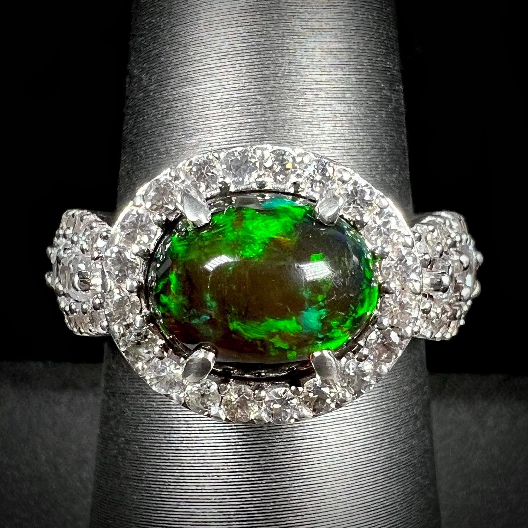 A CZ-accented sterling silver halo ring mounted with a smoked Ethiopian fire opal.  The opal plays green, red, and blue colors.