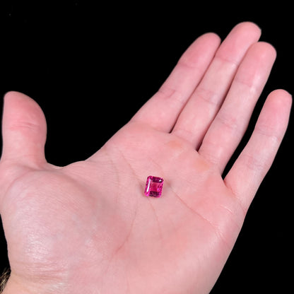 A loose, faceted modified emerald cut hot pink tourmaline stone.