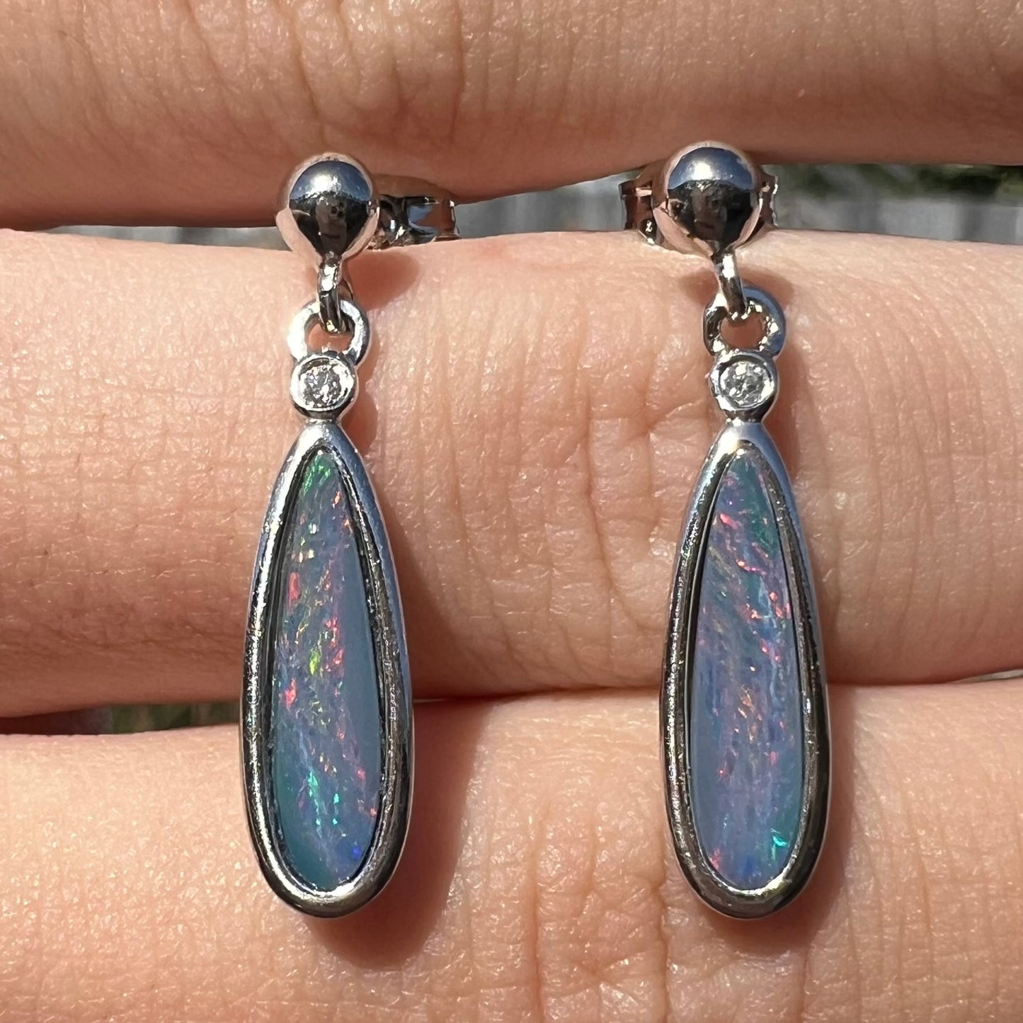 A pair of sterling silver, pear shaped opal doublet dangle earrings.  The opals have a gray body tone with red fire.