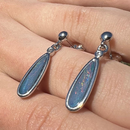 A pair of sterling silver, pear shaped opal doublet dangle earrings.  The opals have a gray body tone with red fire.