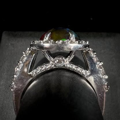 A CZ-accented sterling silver halo ring mounted with a smoked Ethiopian fire opal.  The opal plays green, red, and blue colors.