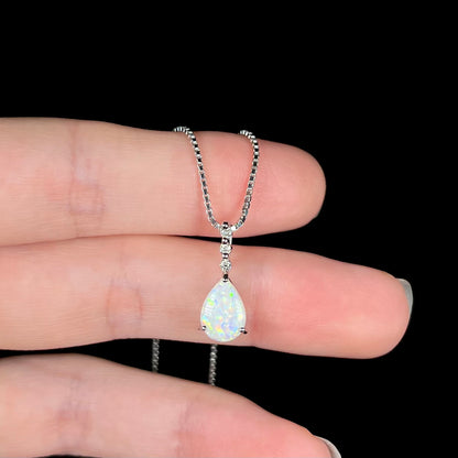 A platinum drop pendant mounted with three diamond accents and a pear shaped opal.