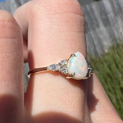 A dainty, pear shaped opal ring mounted in yellow gold with moissanite accents.