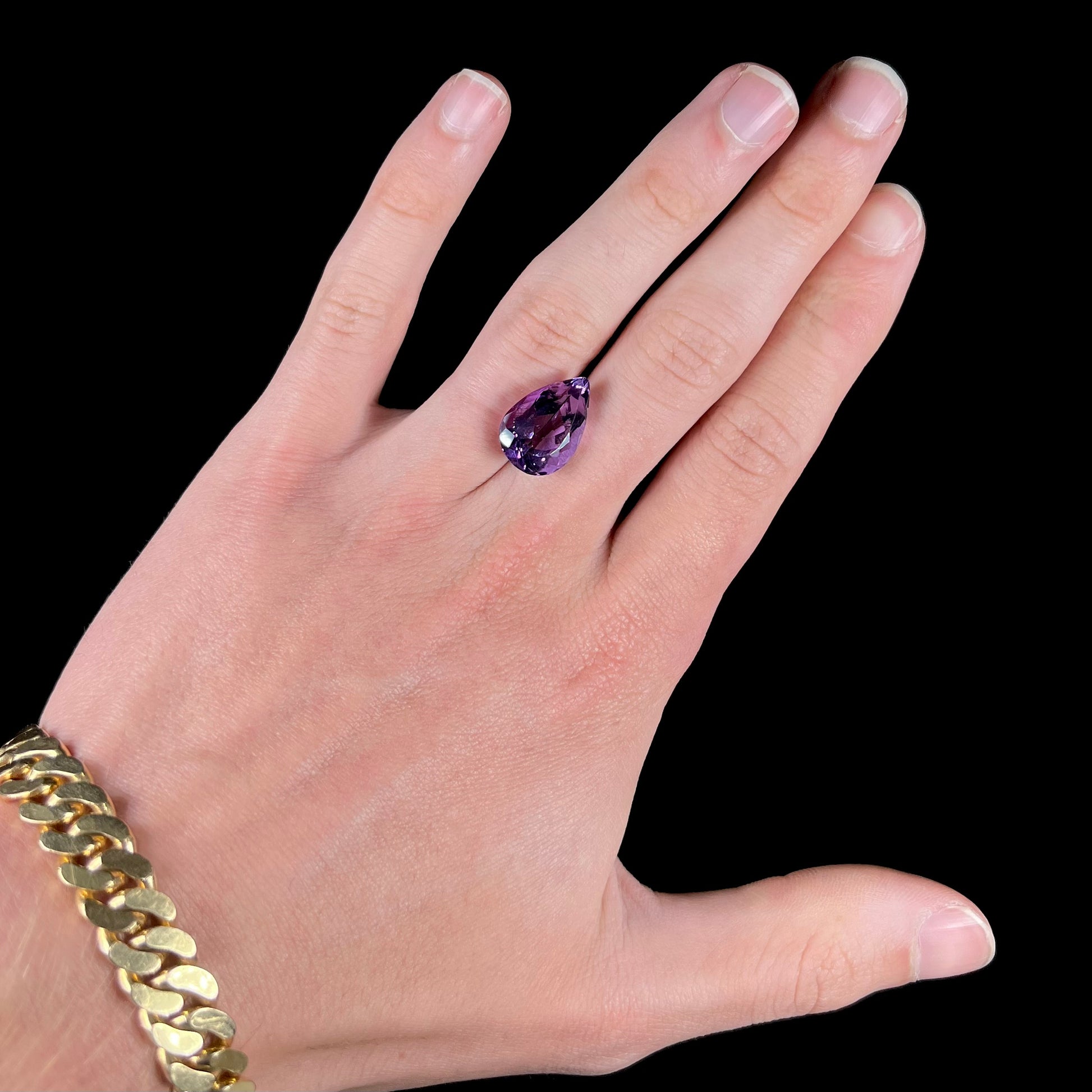 A loose, pear shaped amethyst gemstone.  The stone is a medium purple color.