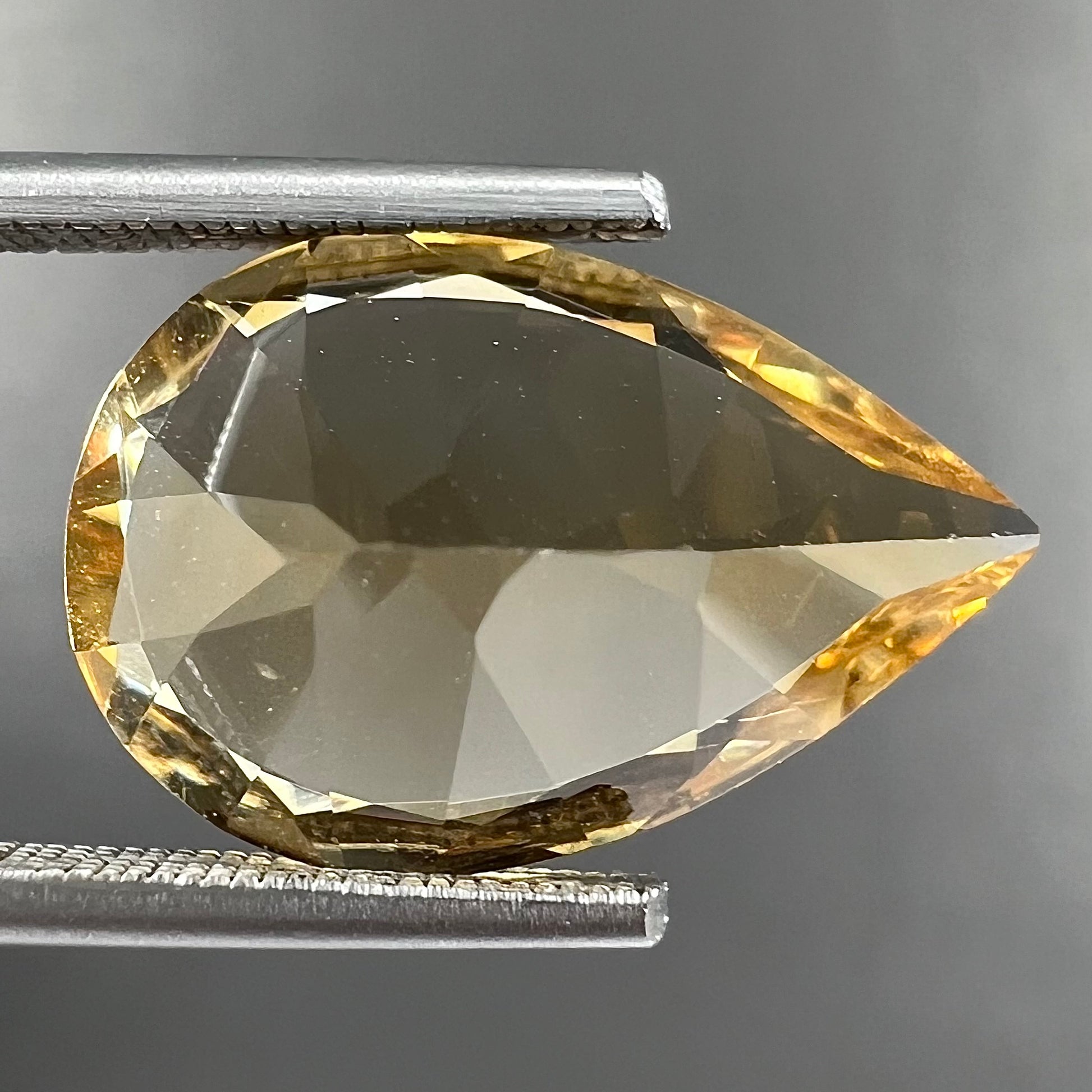 A loose, golden yellow, pear shaped citrine gemstone.