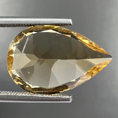 A loose, golden yellow, pear shaped citrine gemstone.